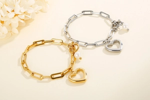 Détails du bracelet chaîne épaisse en acier avec pendentif cœur et perle sur fond beige