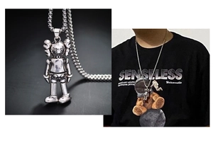 Dettaglio del ciondolo stile KAWS in metallo argento su una lunga catena in titanio