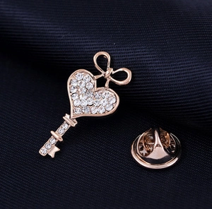 Close-up of rose gold heart-shaped key brooch with rhinestones and bowtie detail