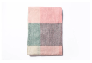 Folded winter scarf with pink and green plaid pattern on a clean white background