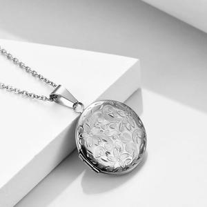 Macro shot of an openable round locket pendant with floral relief and metal O-chain