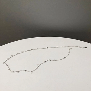 Detailed view of silver choker necklace featuring small metal beads and round disc pendants