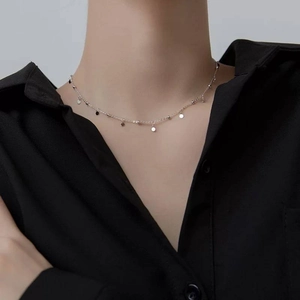 Detail view of a silver choker necklace with shimmering round disc charms on a model