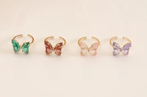 Detailed view of colorful butterfly rings in teal, pink, brown, and purple glass