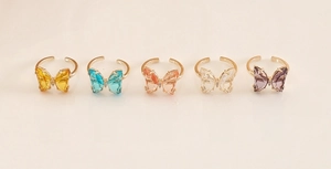 Detail view of adjustable butterfly crystal rings in five various vibrant colors