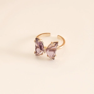 Macro shot of gold-plated open ring featuring a purple crystal butterfly detail