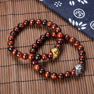 Red tiger eye beaded bracelets with gold and silver skull charms on bamboo mat