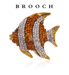 Detail of elegant gold-toned fish brooch featuring orange and white rhinestones