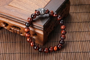 Macro detail of red tiger eye beads and stainless steel skull on a beaded bracelet