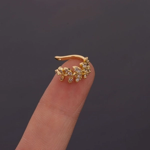 Close-up of gold leaf-shaped ear cuff with sparkling zircon stones worn on finger