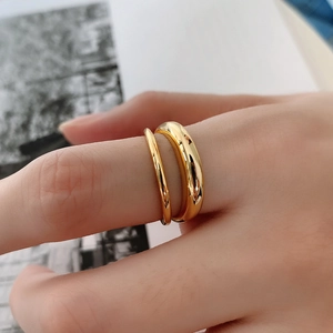 Macro shot of gold double-layer minimalist ring worn on finger over magazine background