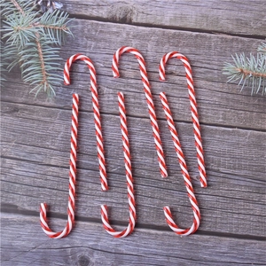 Set of 6 red and white striped acrylic candy cane ornaments on a rustic wooden background