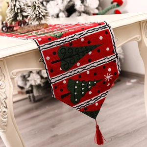 Christmas table runner with green trees and tassels on a vintage white desk