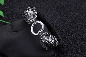 Detailansicht der silbernen Löwenkopf-Anhänger und des schwarzen Lederarmbands für Herren