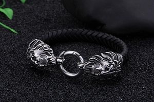 Detail eines geflochtenen Lederarmbands mit zwei Löwenköpfen aus Edelstahl auf Untergrund
