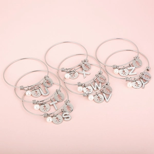 Polished stainless steel letter bracelets with shell charms and pearls on pink background