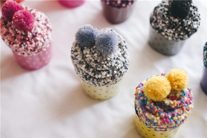 Top view of fluffy cupcake-shaped coral fleece socks with colorful pom-poms and polka dots