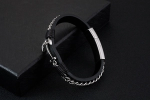 Detail of black silicone bracelet with stainless steel anchor charm and metal chain trim