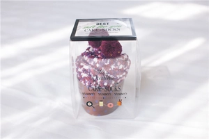 Cupcake-styled gift box featuring thick purple and white coral fleece socks with pom-poms
