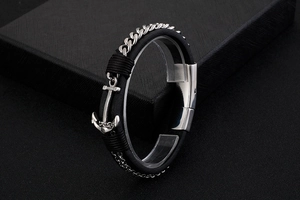 Macro shot of anchor-shaped clasp on woven leather and steel chain bracelet in gift box