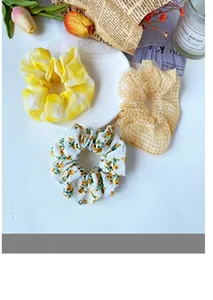 Three-piece hair scrunchie set featuring yellow tie-dye, orange plaid, and floral patterns