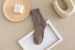 Detail of brown knitted thick socks with ribbed cuffs on minimalist wooden tray