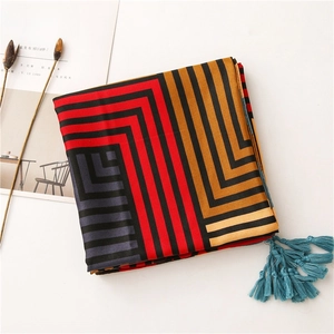 Detail of colorful geometric striped cotton linen scarf with bright cyan tassel accents