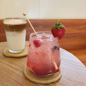 Minimalist transparent glass cups with coffee and juice on woven coasters in a cozy setting