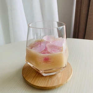 Close-up of geometric glass cup with chilled drink on a round wooden coaster