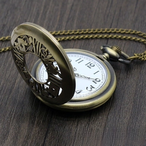 Detailed macro of vintage bronze quartz pocket watch with hollow poker pattern on wood