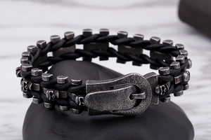 Detail of punk braided leather bracelet featuring skull charms and belt buckle clasp