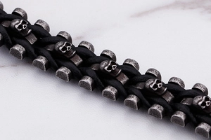 Detailed macro view of woven black leather bracelet with silver skull charms and beads
