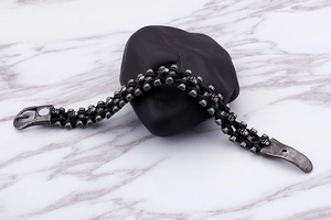 Détail d'un bracelet en cuir tressé noir avec breloque crâne et fermoir magnétique