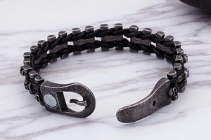 Détail du bracelet en cuir tressé noir avec maillons argentés et fermoir à crochet sur marbre