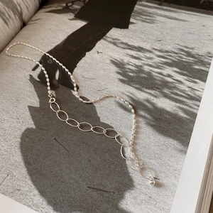 Close-up of 925 sterling silver olive bead necklace with elegant shadow on a book page