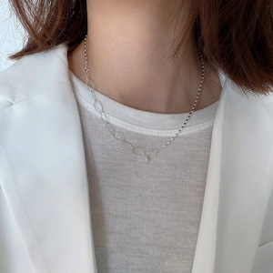 Detailed view of asymmetrical 925 silver necklace with olive beads on a model