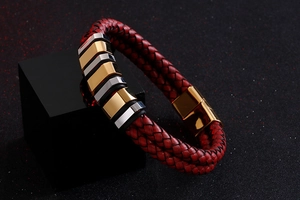 Macro detail of red braided leather bracelet with gold and silver geometric accents
