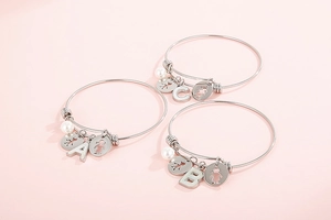 Detailed view of silver stainless steel charm bracelet with shell pearl and letter charms