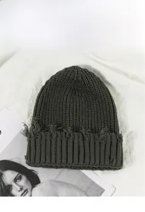 Détail du bonnet en maille avec bords usés et texture côtelée de couleur vert foncé