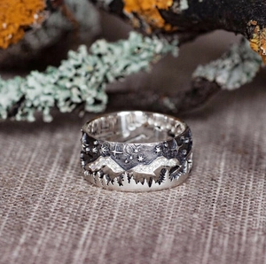 Macro detail of vintage style wolf ring with mountain and forest relief patterns