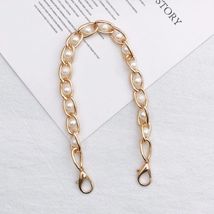 Detail of gold metal chain intertwined with white imitation pearls and lobster clasps