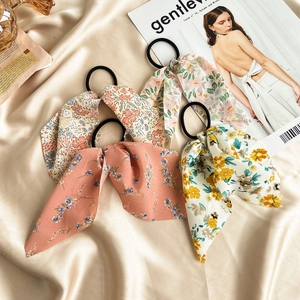 Elastic floral ribbon hair scrunchies in pastel colors on an elegant satin background