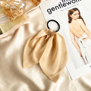 Elegant champagne gold satin bow hair scrunchie shown on silky fabric with soft lighting