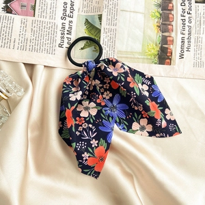 Detail of high-elastic navy blue floral scrunchie with ribbons on vintage newspaper background