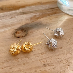 Detailed view of silver and gold irregular lava stud earrings on a natural wood surface