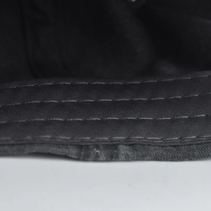Close-up of triple-stitched seams on high-quality black cotton twill baseball cap fabric