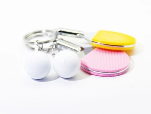 Macro shot of mini yellow and pink table tennis racket keychains with white balls