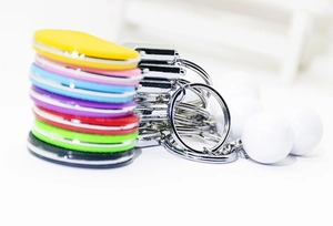 Close-up of colorful mini table tennis paddle keychains with white ball pendants