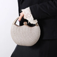 Detailed view of a gold pleated evening clutch with metallic handle and ball clasp