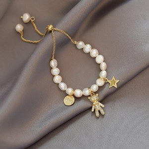 Detail of baroque pearl bracelet featuring micro-pasted bear and LOVE tag on silk